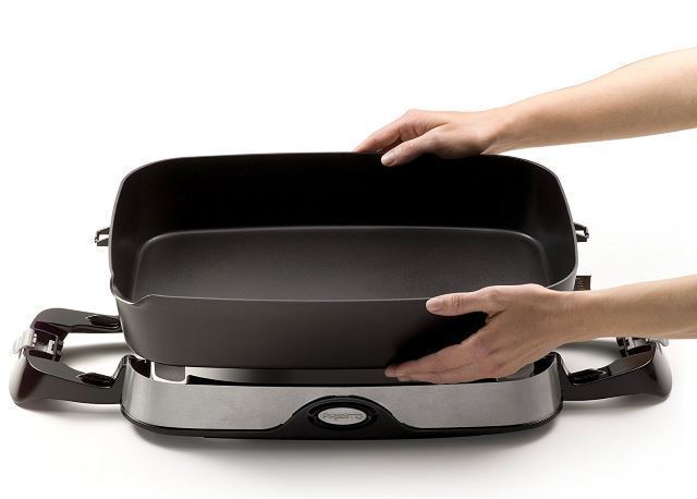 holding an electric skillet Hands holding an electric skillet on white background.