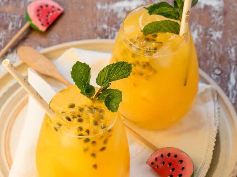 Passion Fruit & Ginger Mojitos Passion Fruit & Ginger Mojitos in wine glasses with watermelon swizzle sticks.