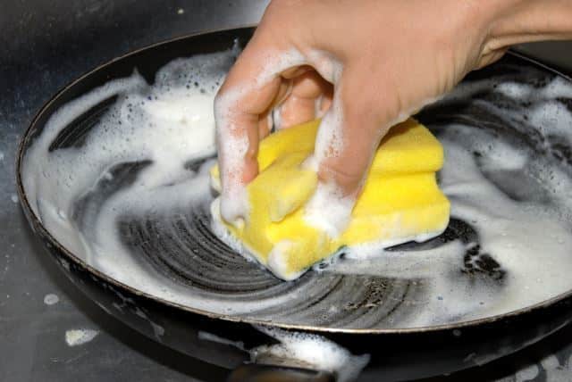 Washing frying pan with sponge.