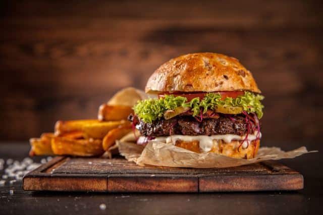 Juicy Hamburger Juicy Hamburger on a cutting board with fries.