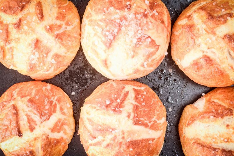 How to Make Pretzel Bread Final 1 6 pretzel bread rolls layed flat on a pan.