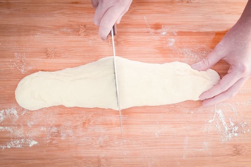 How to Make Pretzel Bread Step 13 Cutting roll in half on floured surface.