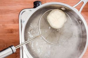 Boiling a dough ball in pot of boiling water.