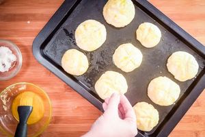 Sprinkling salt onto rolls on a pan.