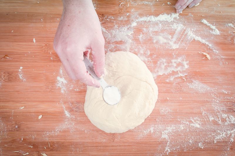 How to Make Pretzel Bread Step 9 Adding salt to dough on floured surface.