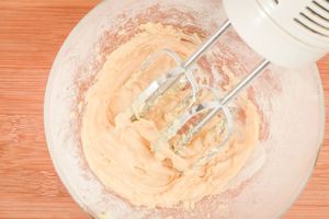 Using a hand mixer to combine vanilla, butter and sugar.