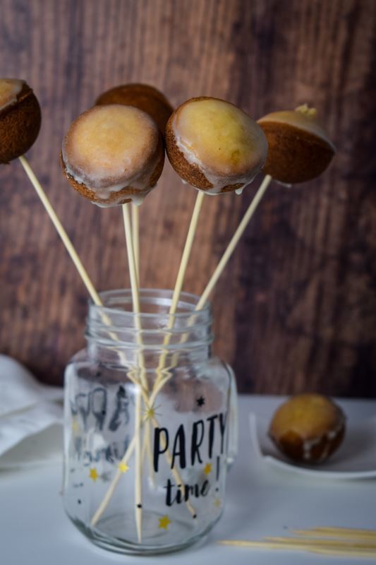 How to Make Cake Pops with a Cake Pop Maker 6 Glazed cake pops in a glass jar, wood background.