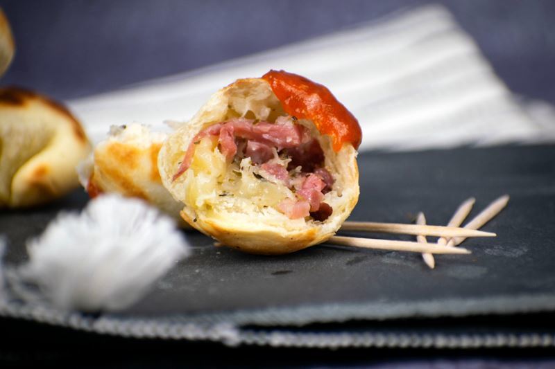 Cake Pop Maker Pizza Balls 7 Pizza ball cut in half with tomato sauce on top, toothpicks on the side.