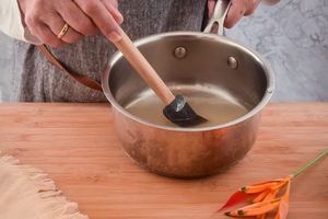 Woman's hand mixing a sugar and water mixture in a pot.