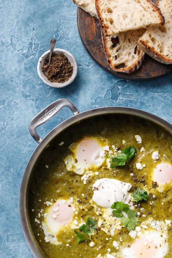 Tomatillo Shakshuka in a pan, on blue background.