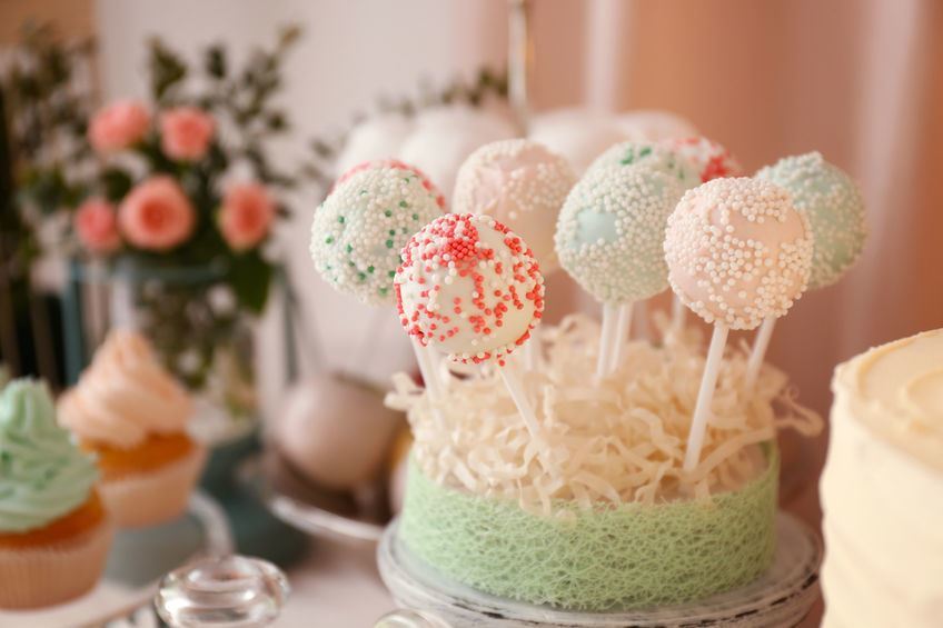 Colorful cake pops on blurred background Cake pops in a loofah stand.