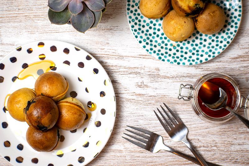 Pancake cake pops covered in maple syrup on a white plate with polka dots.