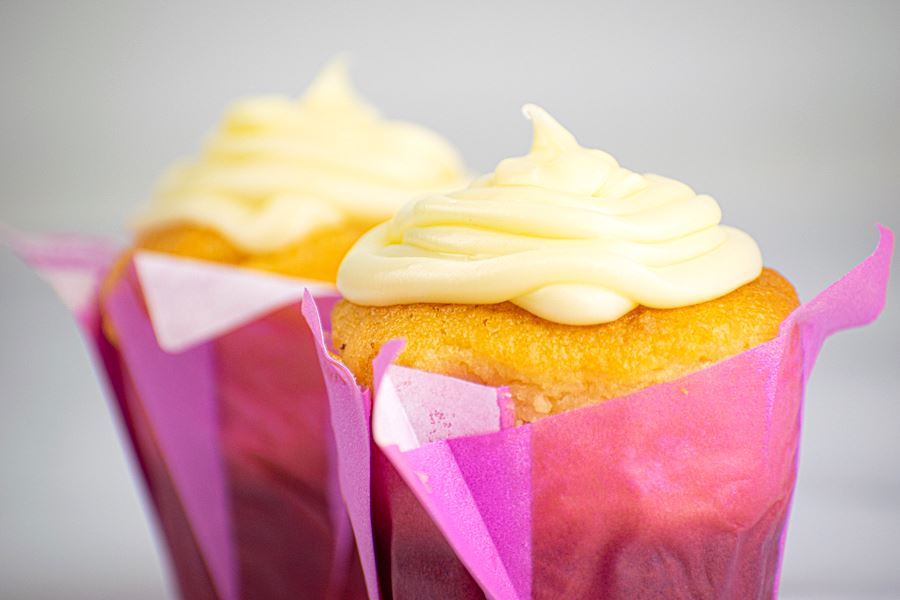 Butter Cream_3 2 cupcakes with buttercream frosting in purple wrappers.