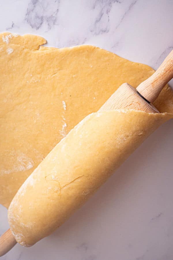How to Make Cinnamon Rolls_13 Rolling pin with cinnamon bun pastry on marble counter top.