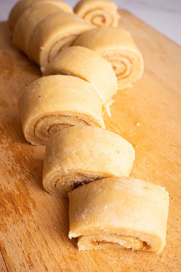 How to Make Cinnamon Rolls_17 Raw cinnamon buns on wooden cutting board.