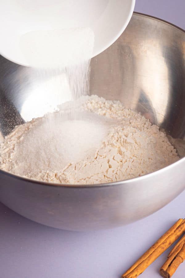 How to Make Cinnamon Rolls_5 Cinnamon bun dough ingredients in a metallic bowl, cinnamon sticks on the side.