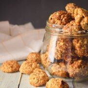 Electric Skillet Oatmeal Cookies in a clear jar, on white wooden background.