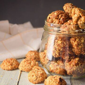 Electric Skillet Oatmeal Cookies in a clear jar, on white wooden background.