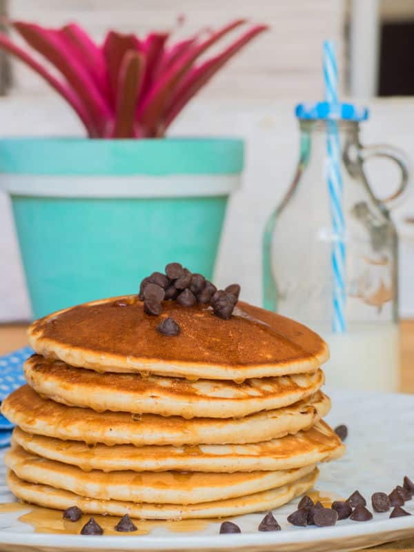 Electric Skillet Pancakes 2 - IntheKitch Pancakes piled on a plate with chocolate chips and maple syrup.