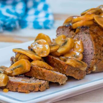 Meatloaf covered in a mushroom sauce on a serving dish.