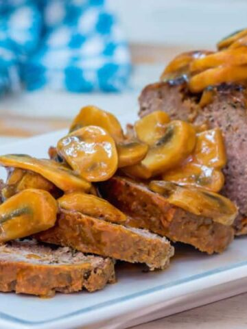 Meatloaf covered in a mushroom sauce on a serving dish.