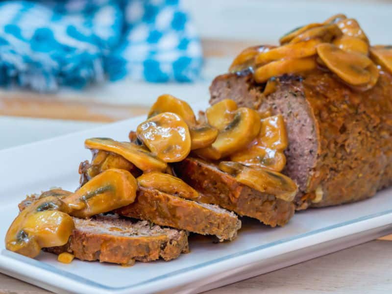 Meatloaf covered in a mushroom sauce on a serving dish.