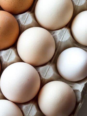 White and brown eggs in a carton.