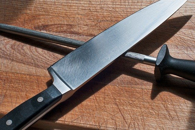 Chefs Knife and knife sharpener on cutting board.
