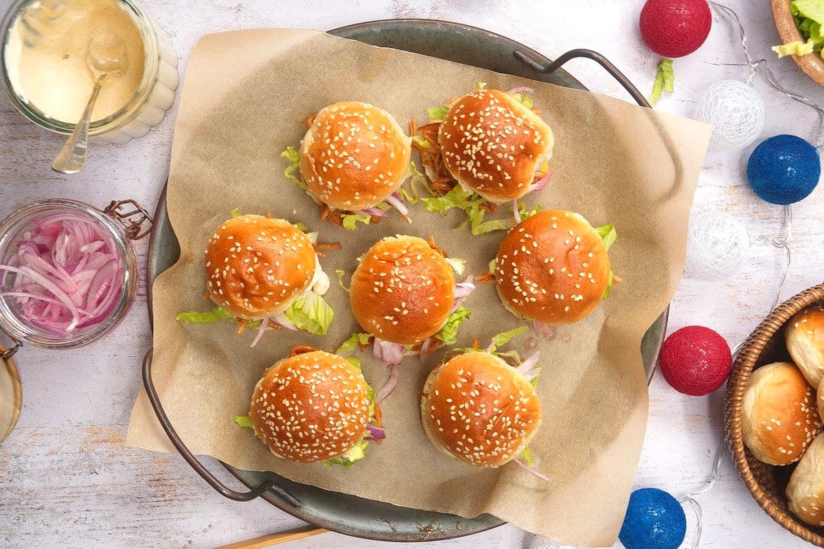 Pulled pork sliders on parchment lined serving tray with 4th of July decorations.