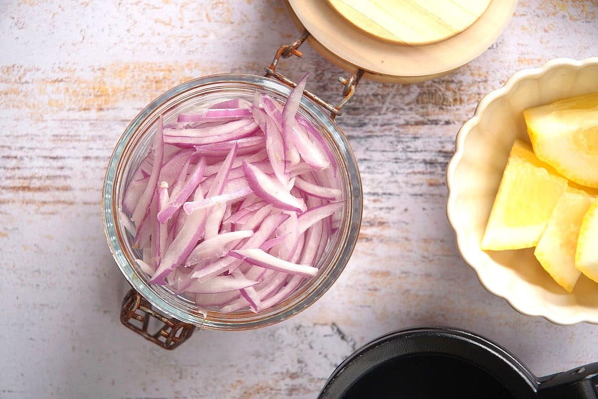Red onion slices marinated in lemon juice in jar.