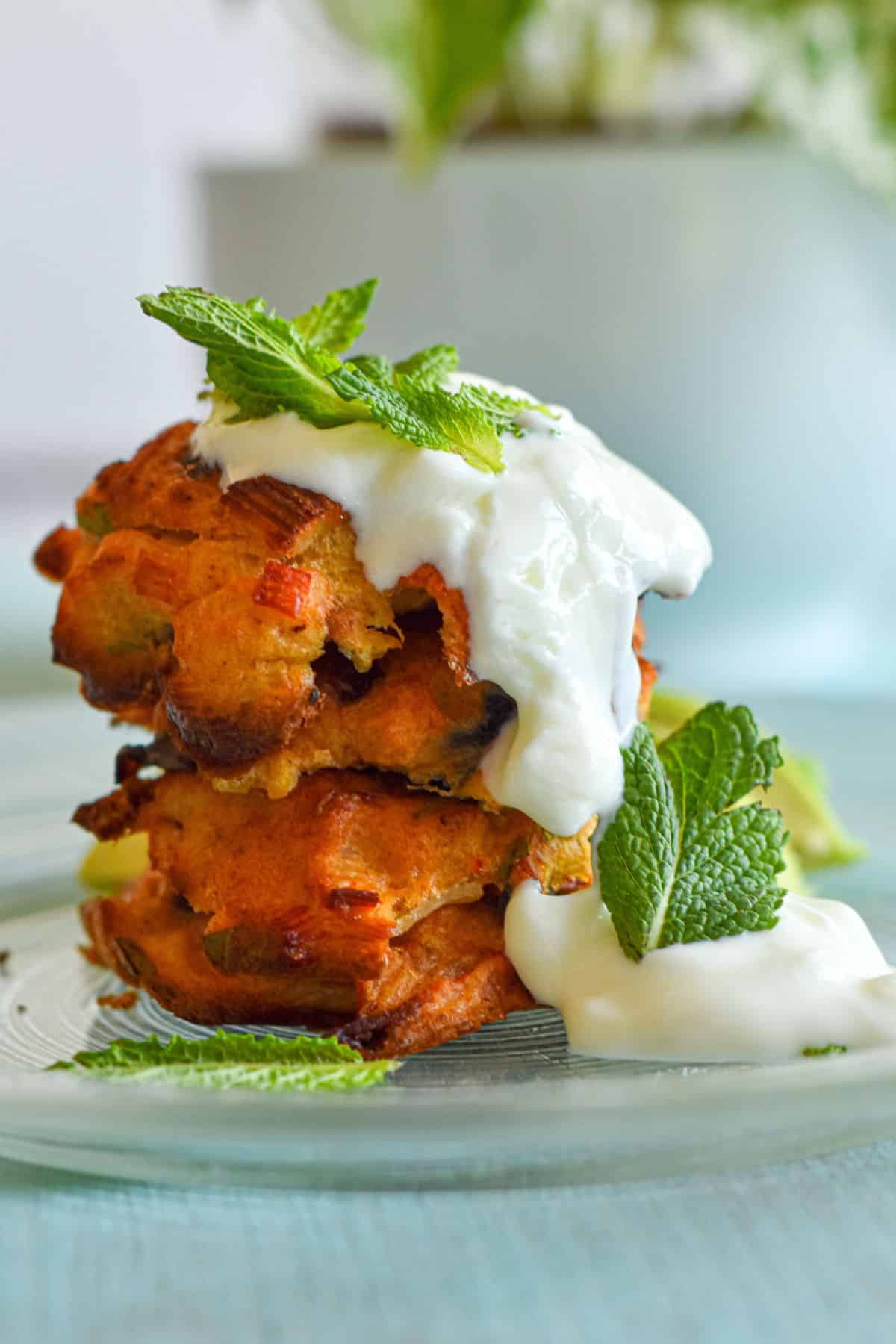 Crab cakes stacked on plate with yogurt.