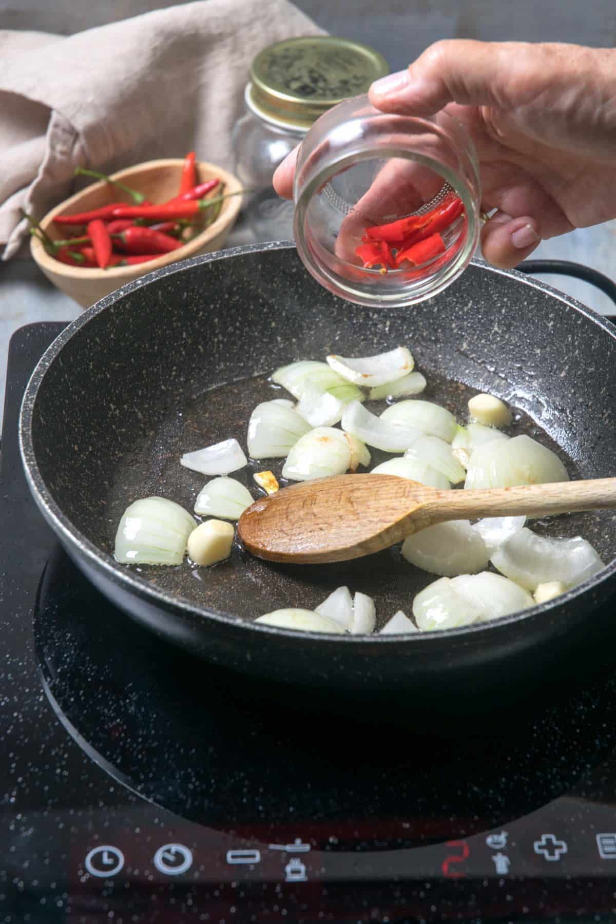 Chopped onions, chilies and garlic in a frying pan.