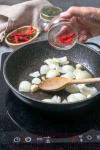 Chopped onions, chilies and garlic in a frying pan.
