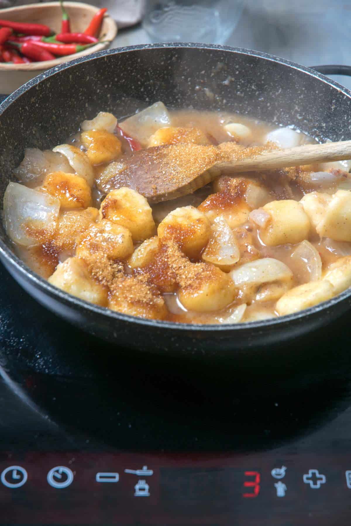 Sliced bananas in a frying pan with apple cider vinegar and brown sugar.