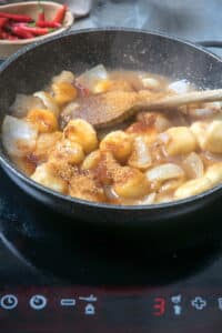 Sliced bananas in a frying pan with apple cider vinegar and brown sugar.