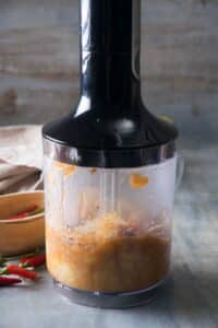 Banana ketchup in a blender, red chilies on the side.