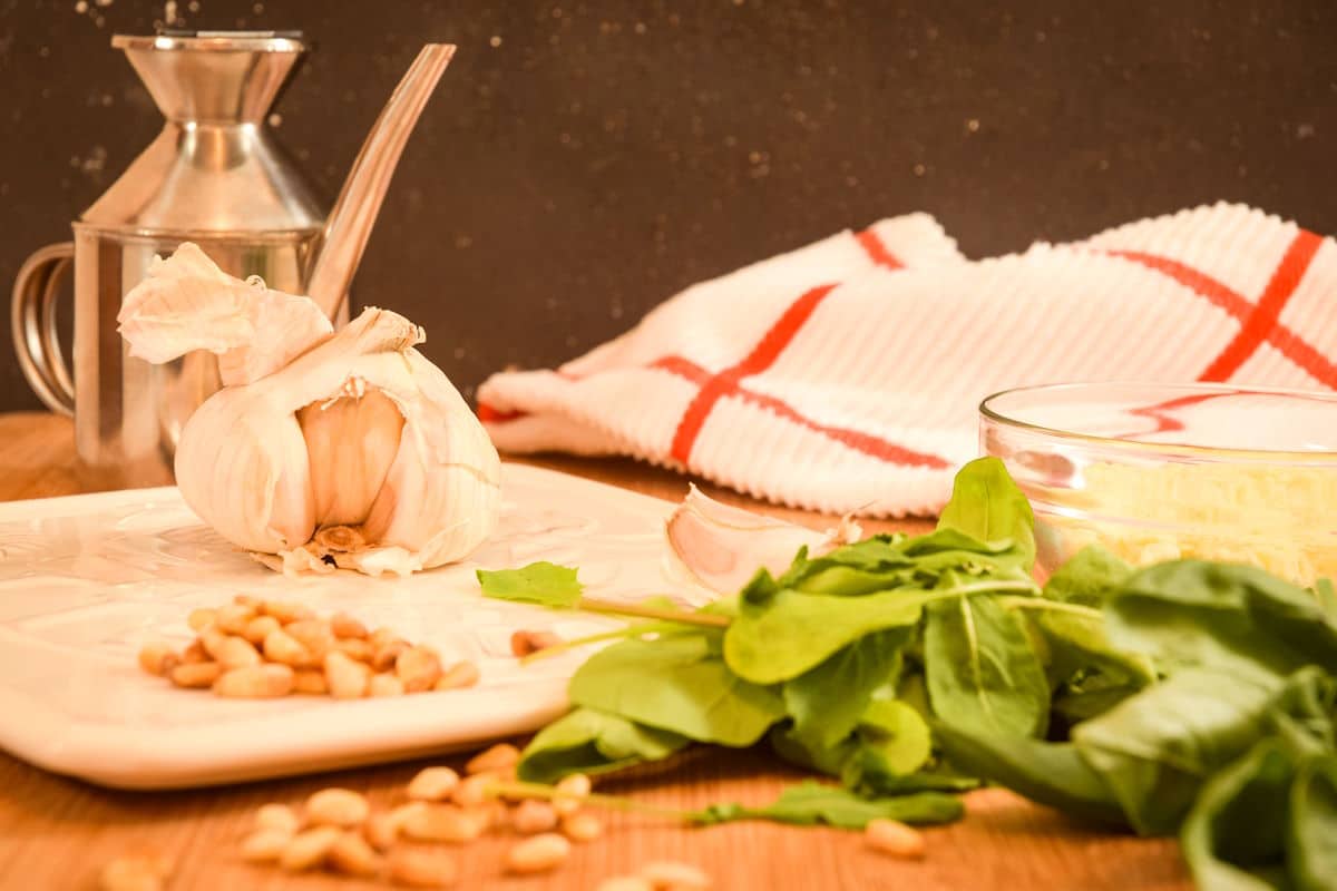 Basil pesto ingredients prepped on wooden table.