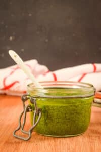 Basil pesto in a small glass jar.
