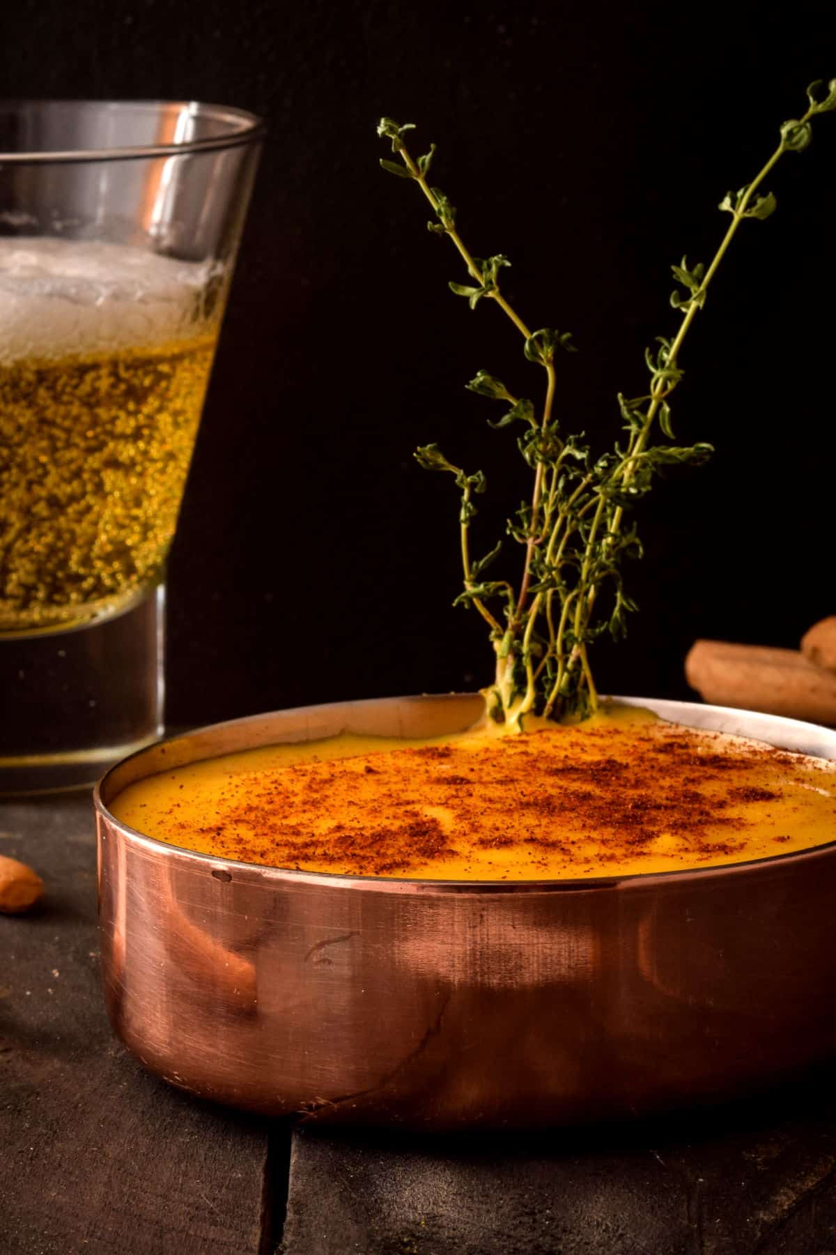 Beer cheese dip in a copper pot with a glass of beer on the side.