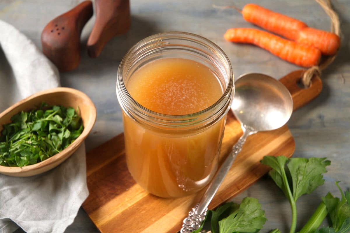 Bison bone broth in jar on a wooden cutting board.