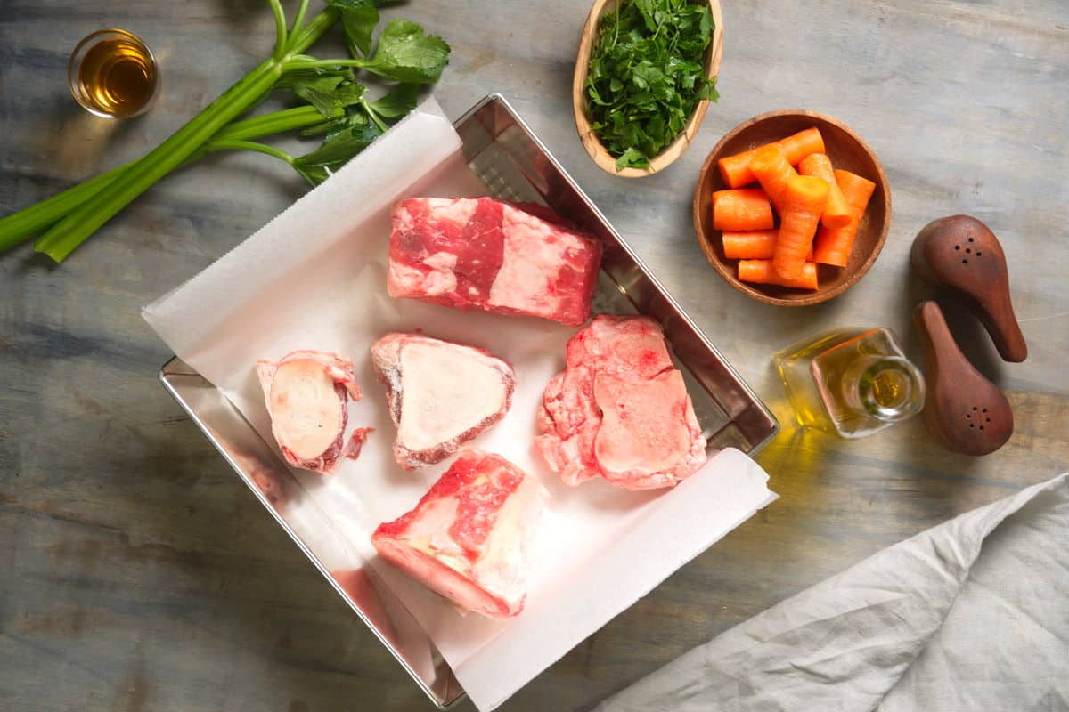 Raw bison bones in baking pan with parchment paper.