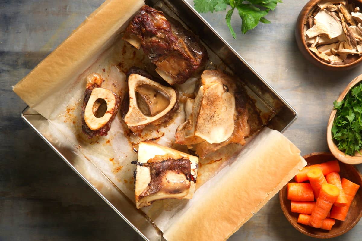 Roasted bison bones in baking pan with parchment paper.