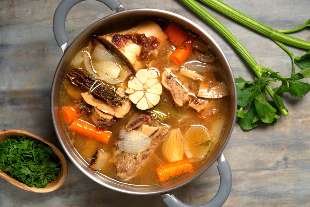 Bison bone broth with vegetables in large stock pot.