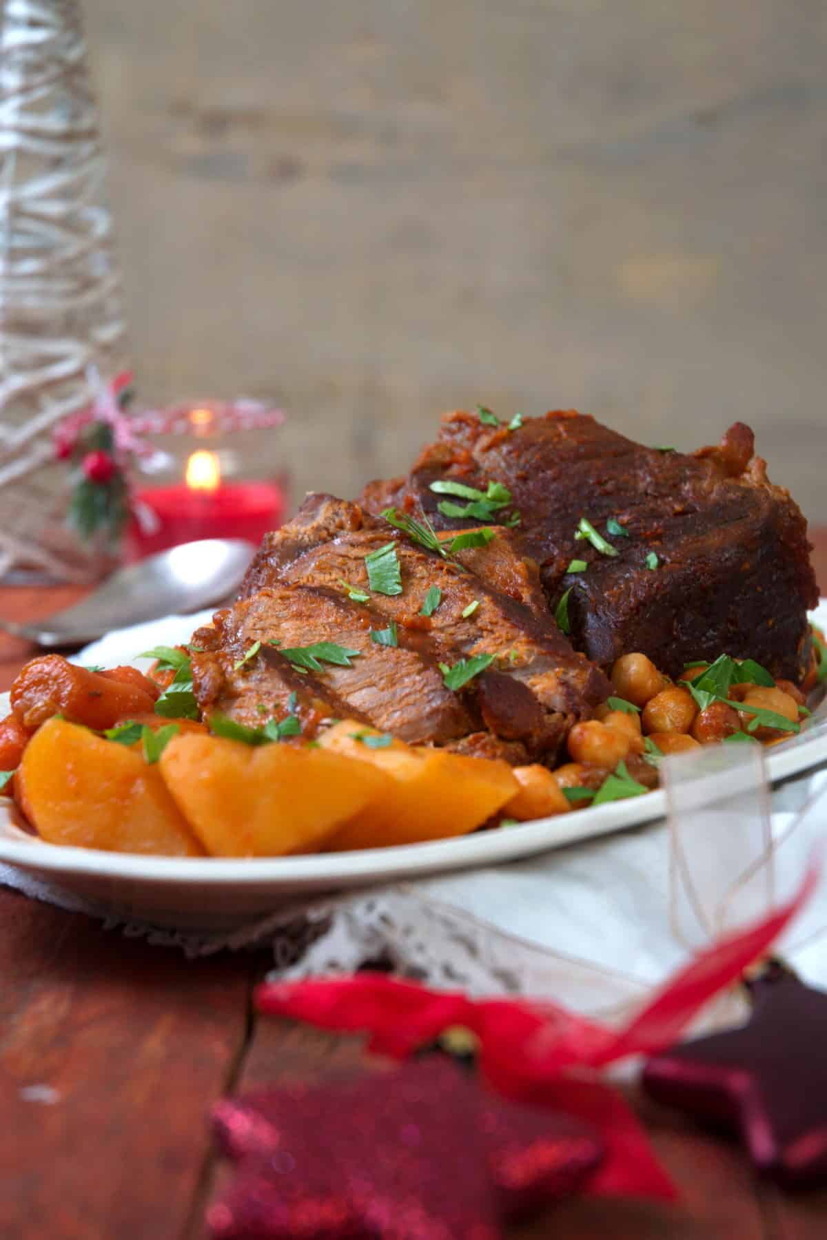 Sliced bison roast on a white serving dish with Christmas decorations.
