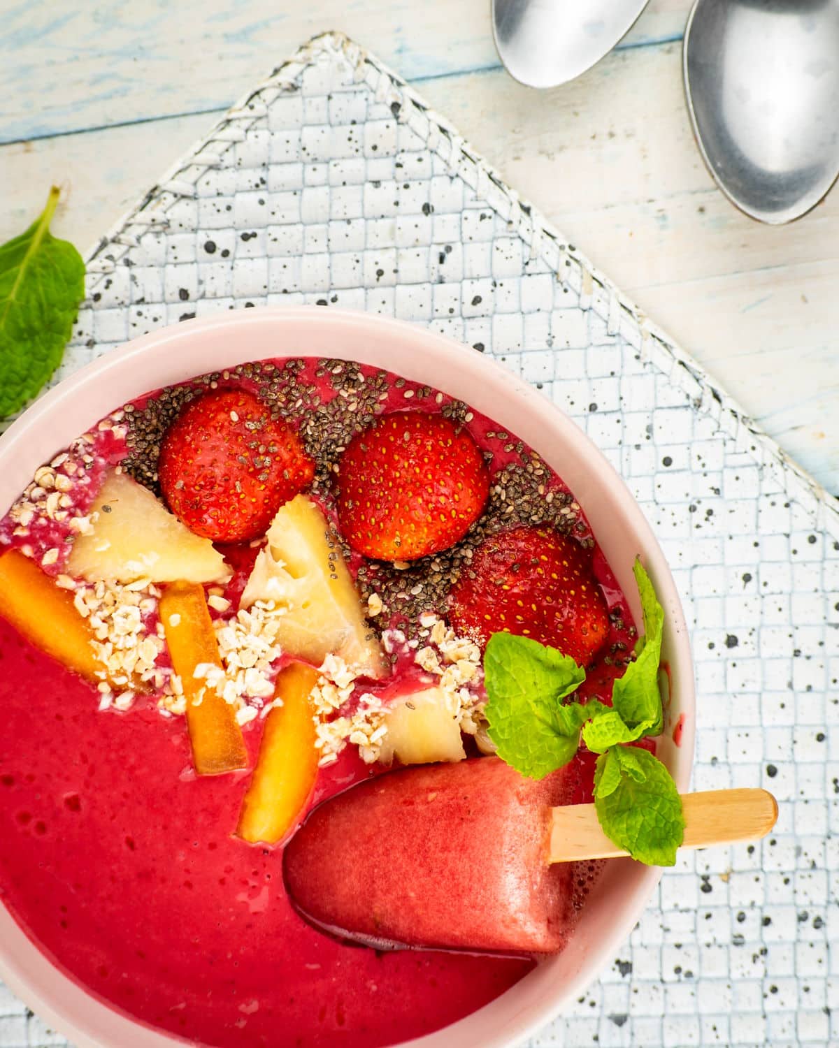 Blackberry smoothie in a bowl with watermelon popsicle and fresh toppings.