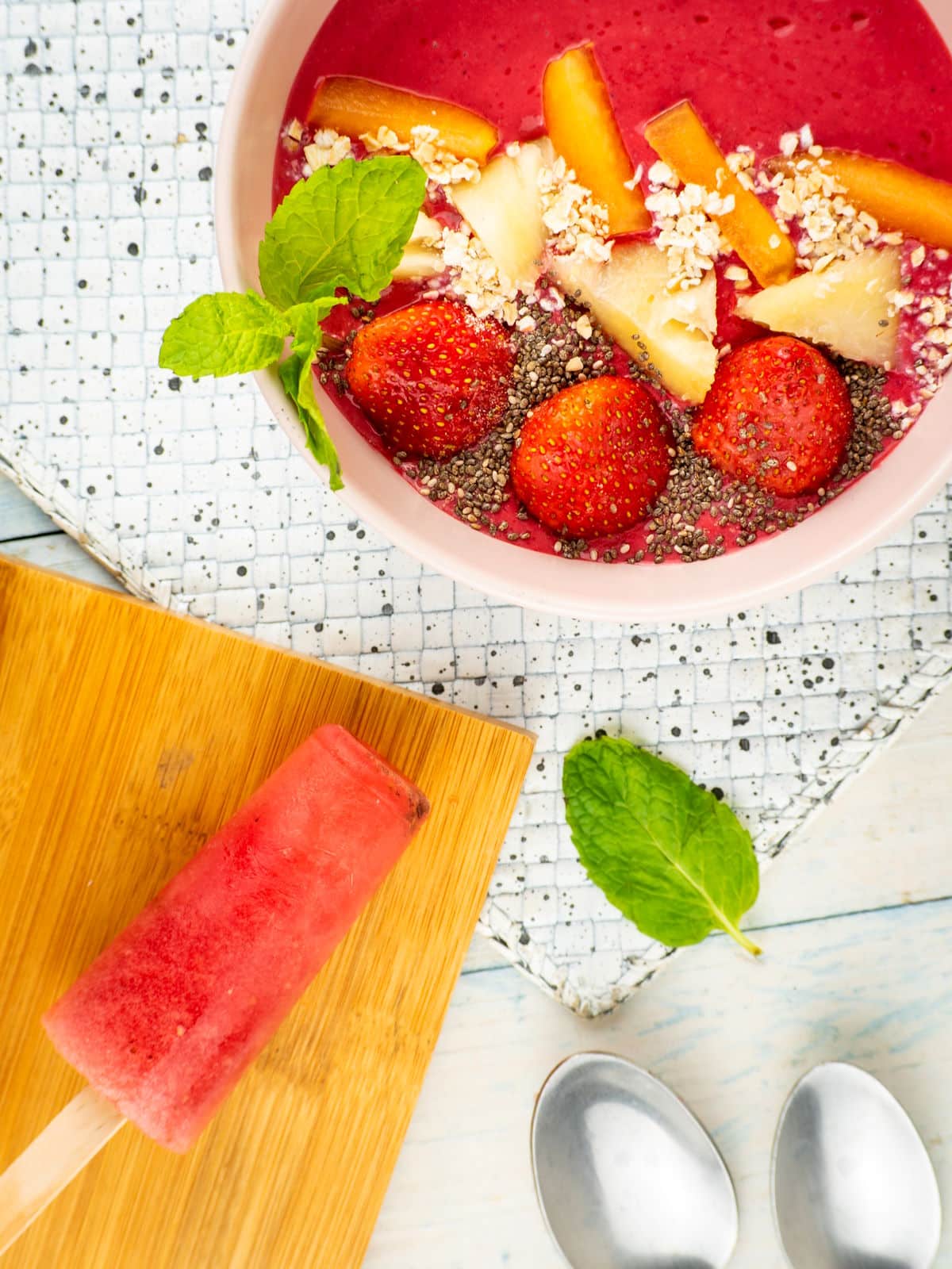 Blackberry smoothie in a bowl with watermelon popsicles and fresh mint leaves.