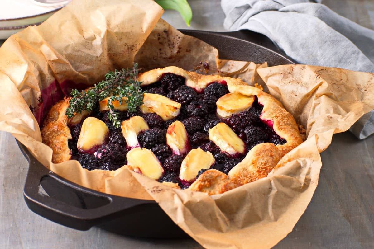 Blackberry galette with brie and thyme in a parchment lined cast iron pan.