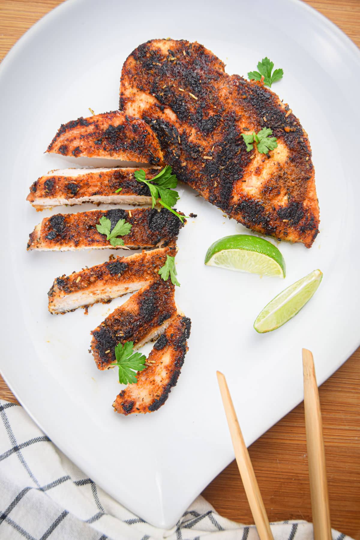 Blackened chicken breasts with parsley and lime wedges.