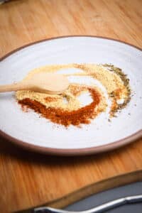 Cajun spices on plate with small wooden spoon.