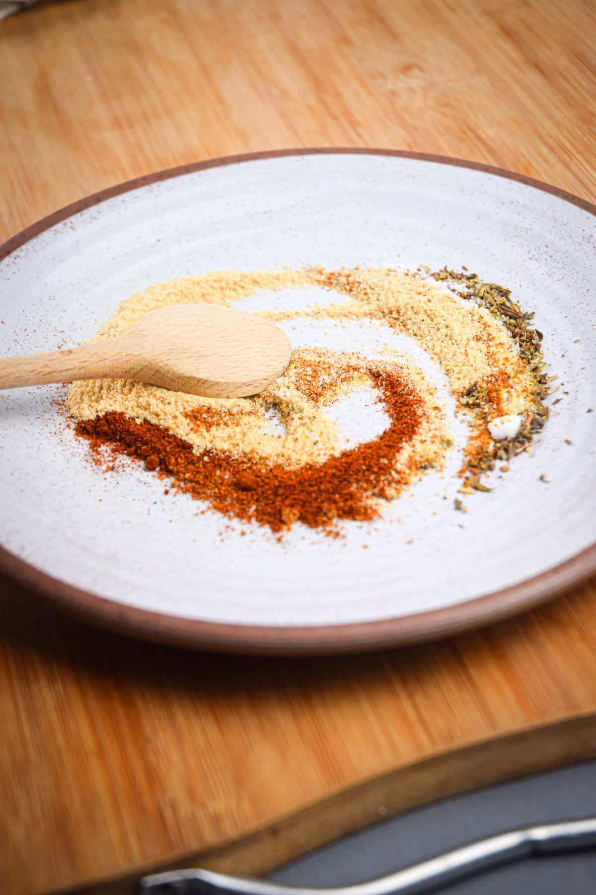 Cajun blackening spices on plate with small wooden spoon.